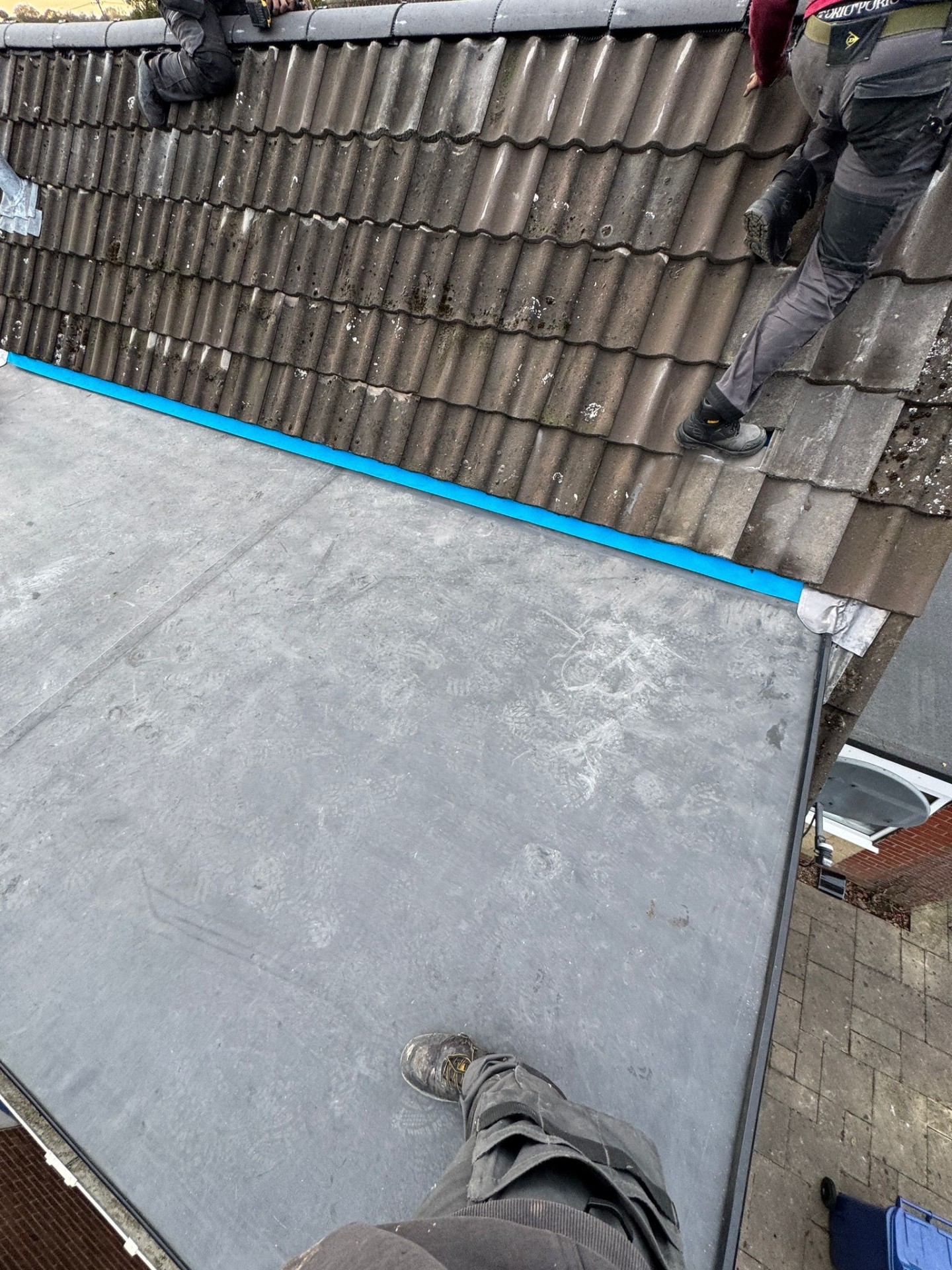 Flat roof junction between pitched tiles and new membrane during EPDM installation