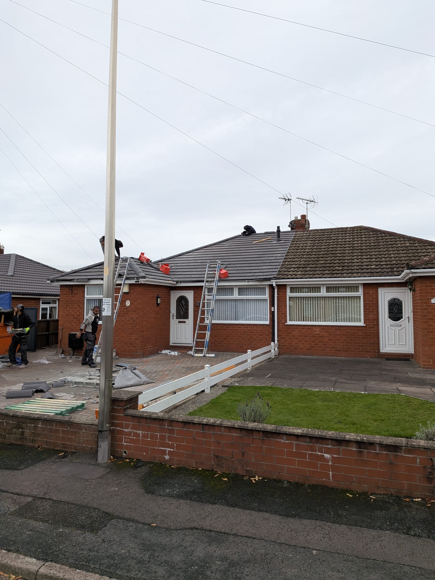 Bungalow re-roof in progress with workers laying new tiles in a Staffordshire neighbourhood