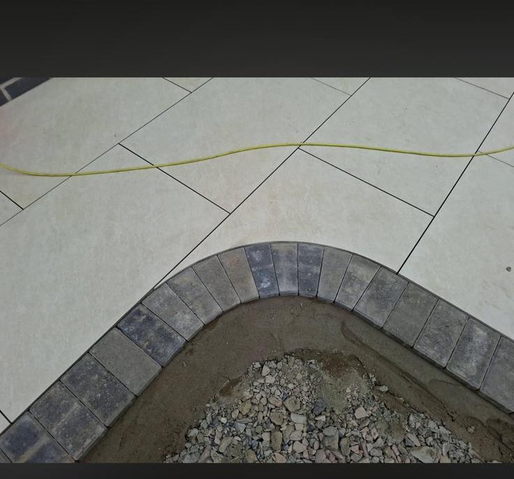 Close-up of porcelain patio meeting a curved charcoal block paving border